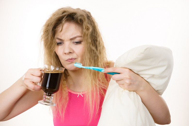 woman holding toothbrush and coffee